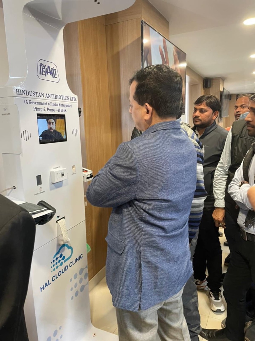 A man using a Health ATM while others look on